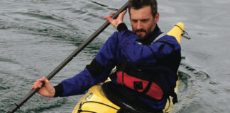 man demonstrates the bow draw in his sea kayak