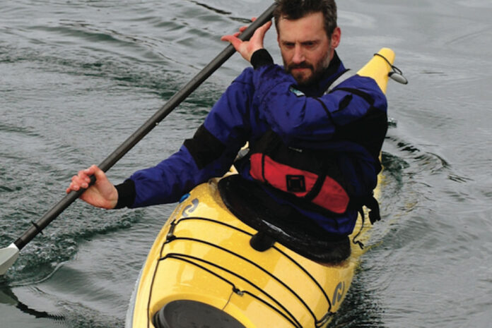 man demonstrates the bow draw in his sea kayak