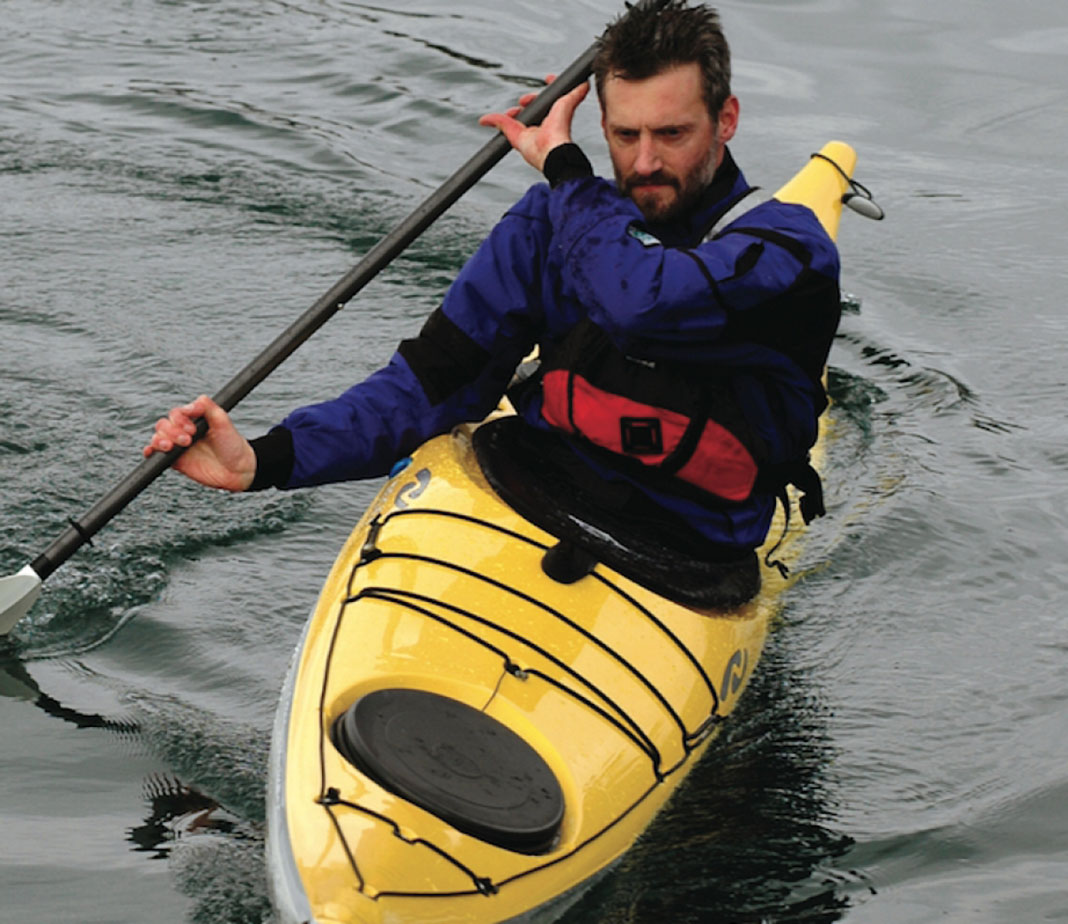 man demonstrates the bow draw in his sea kayak