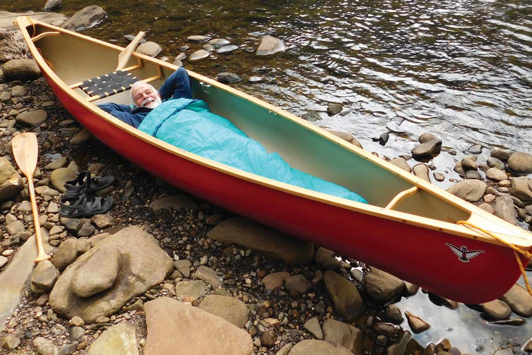 man sleeping in a canoe on land