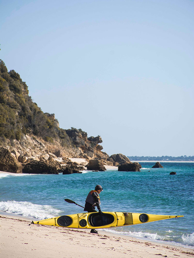 sea kayaker picks up boat and prepares to launch into the ocean
