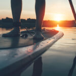 Paddleboard Types You Should Know About Before You Buy person standing and paddling on a SUP at sunset