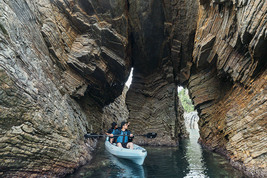 paddlers in a kayak explore oceanside caves