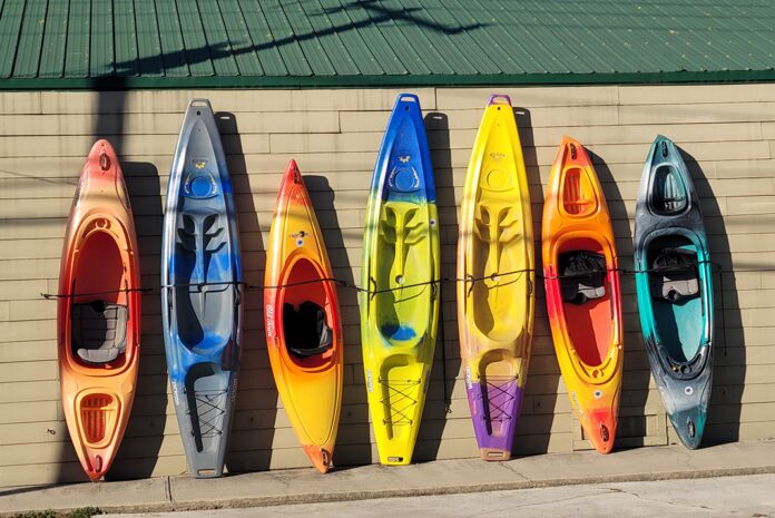 group of kayaks of different sizes lined up outside a building