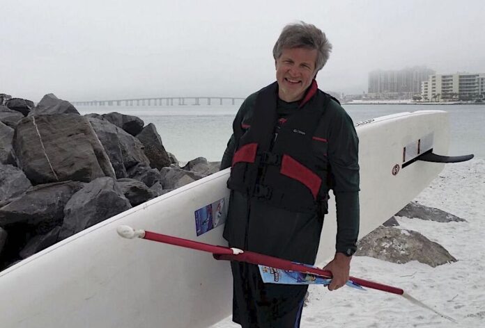 David Schink with his paddleboard on the beach in Destin, Florida
