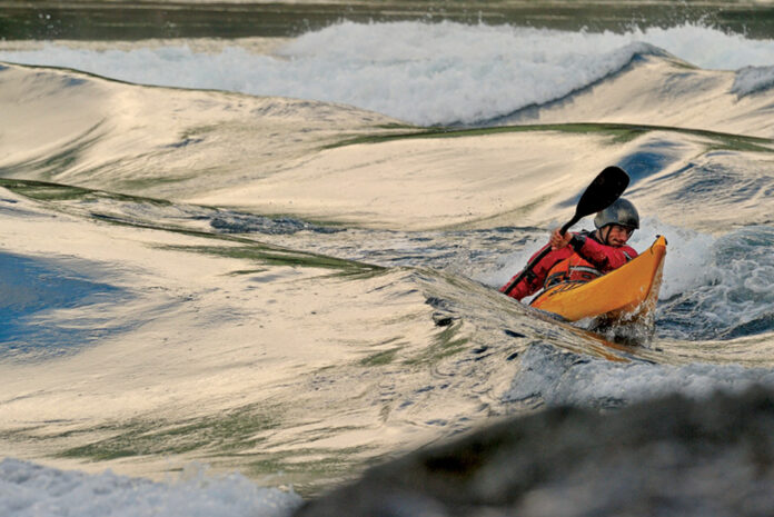 sea kayaker paddles in waves