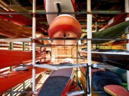 Set of water colorful kayaks on shelves in storage