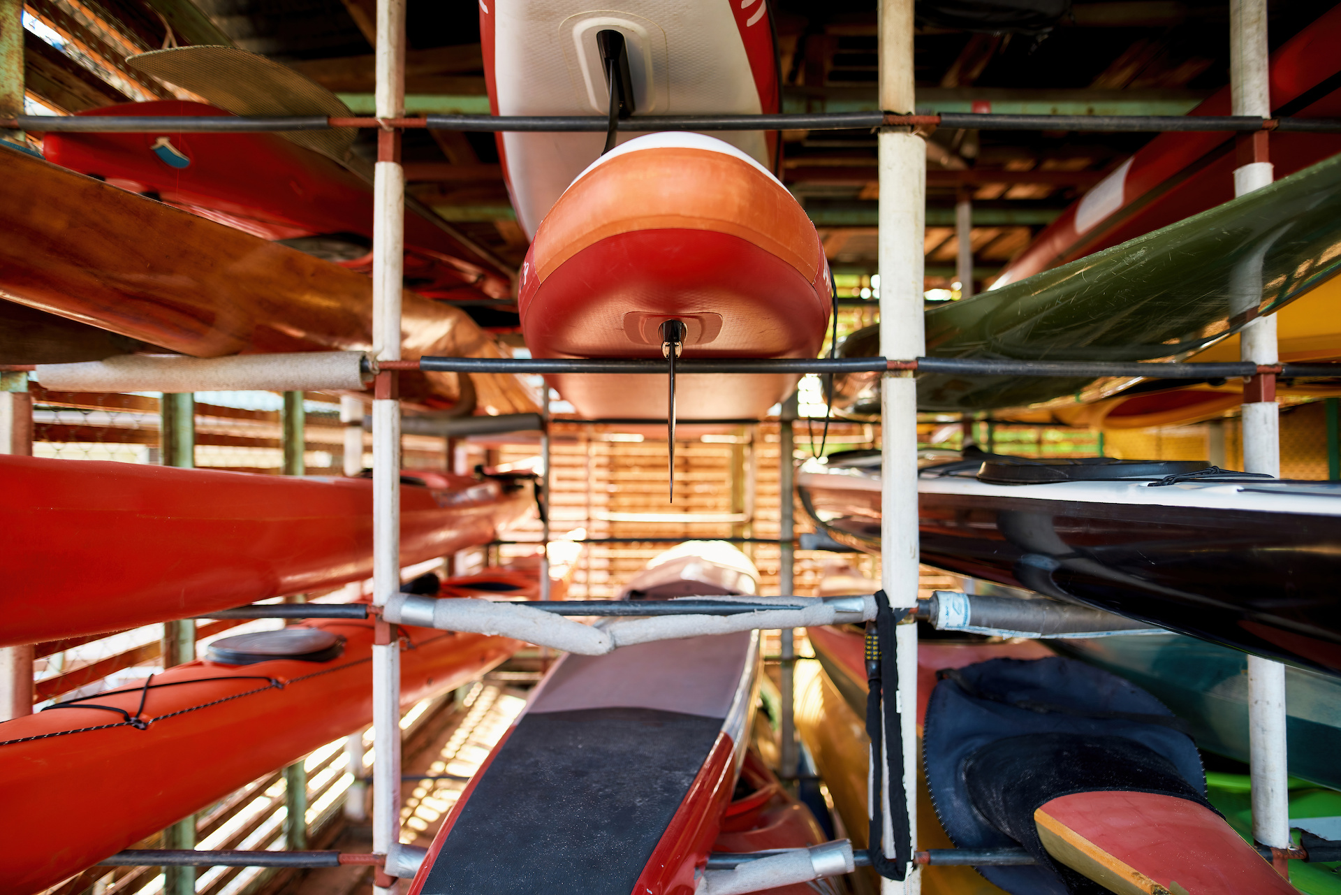 Set of water colorful kayaks on shelves in storage