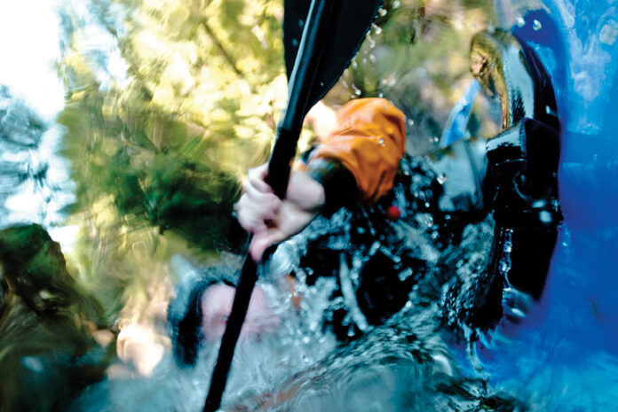 underwater shot of a person completing a whitewater kayak roll