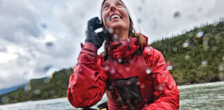 woman looks up at the sky during a rainy canoe trip