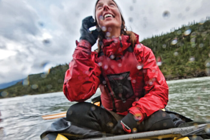 woman looks up at the sky during a rainy canoe trip