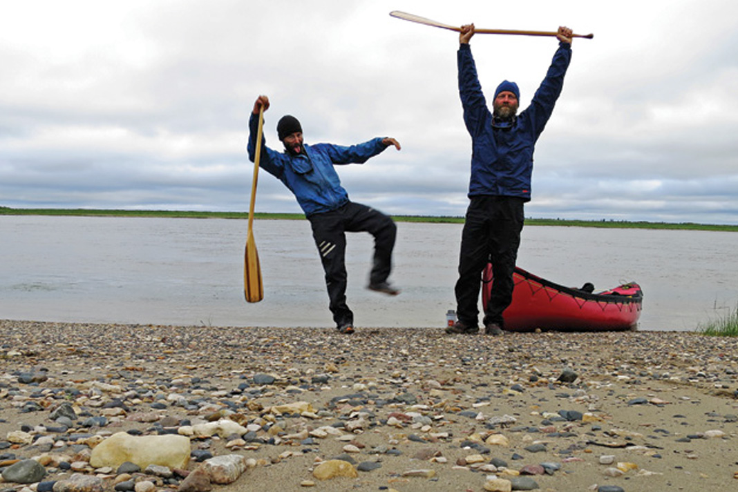 two paddlers celebrate on shore at the end of their expedition