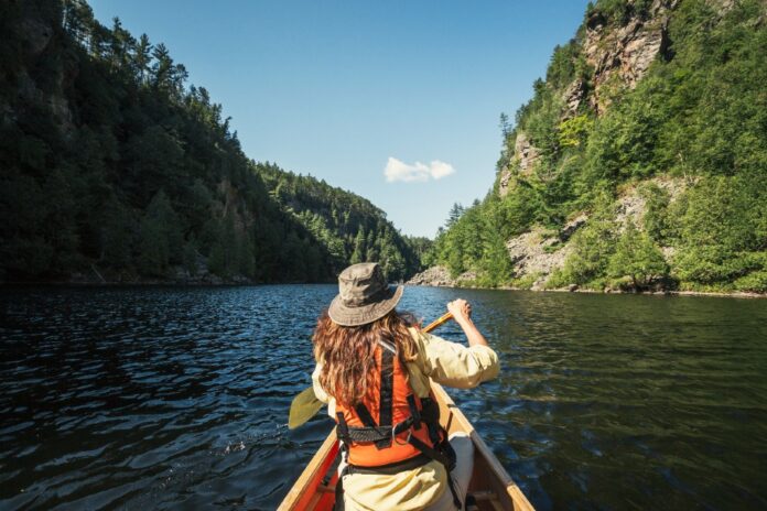 woman paddles a canoe through Barron Canyon in Algonquin Park