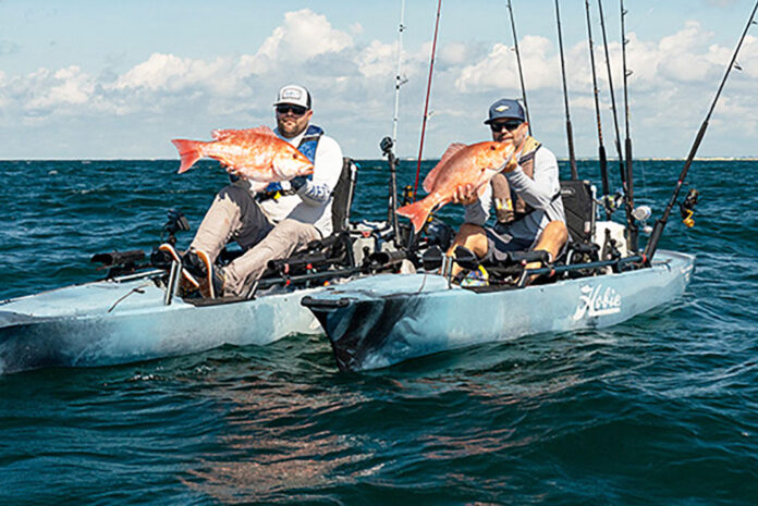 two anglers hold up fish caught on kayaks equipped with the Hobie MirageDrive 360