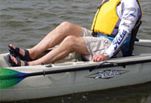 person demonstrates how to adjust the fit of a pedal kayak