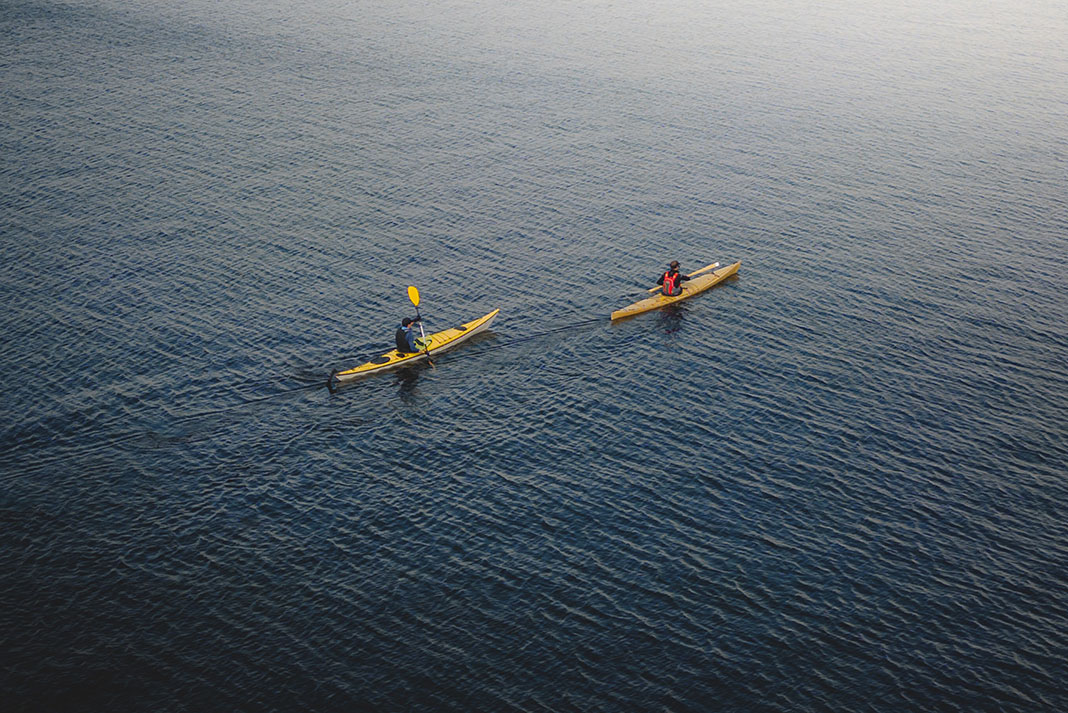 two people paddle in the water on touring kayaks