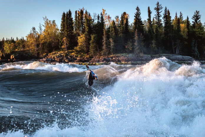 Ben Marr surfs a wave on the Nelson River in Manitoba at sunrise