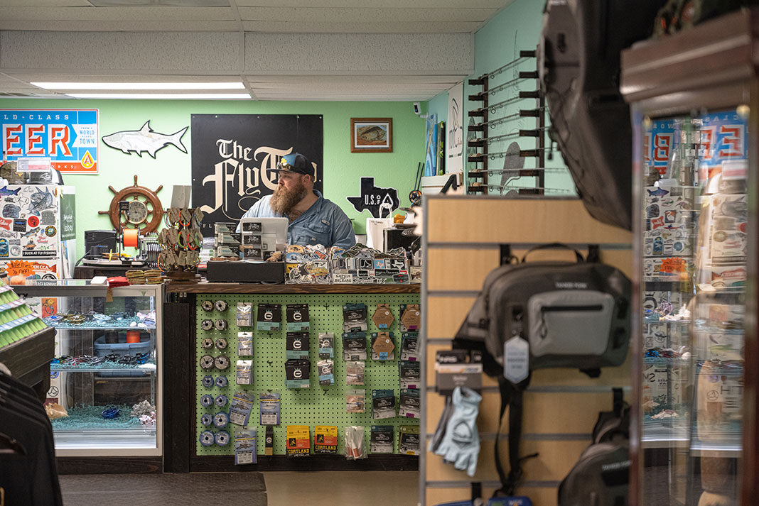 man stands behind the counter at a fly shop in Texas