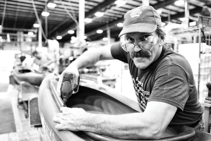 man works on a kayak on the Old Town assembly line