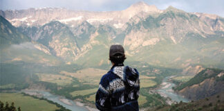 man looks out over the Vjosa River and surrounding mountains