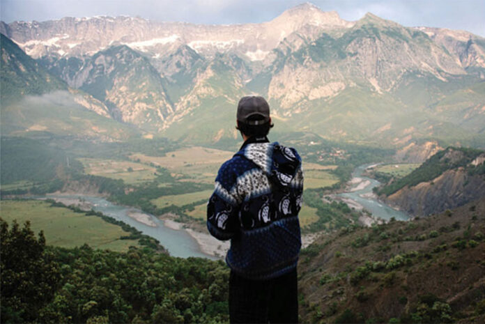 man looks out over the Vjosa River and surrounding mountains