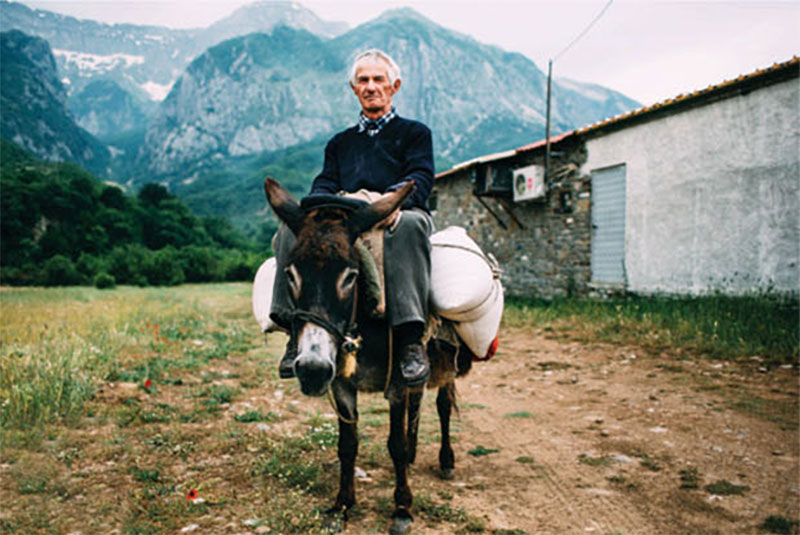 a local man sits on a donkey in the Balkans