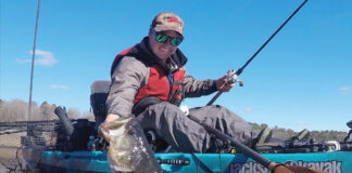 kayak angler holds up a big river largemouth bass