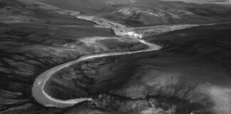 Overhead black and white photo of a river winding through a rocky valley