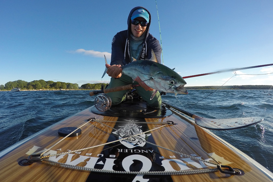 man holds a fish caught from a paddleboard while sight fishing