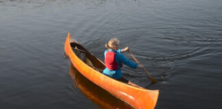 woman demonstrates how to paddle a canoe backwards