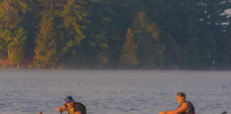 Two men paddle a canoe in golden light at the start of the Muskoka River X race