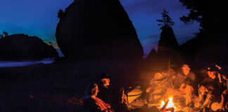 a group of people sit around a campfire while on a minor kayak adventure