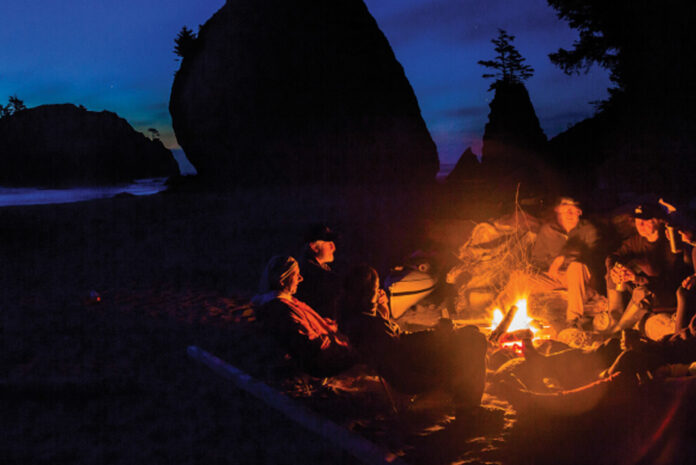 a group of people sit around a campfire while on a minor kayak adventure