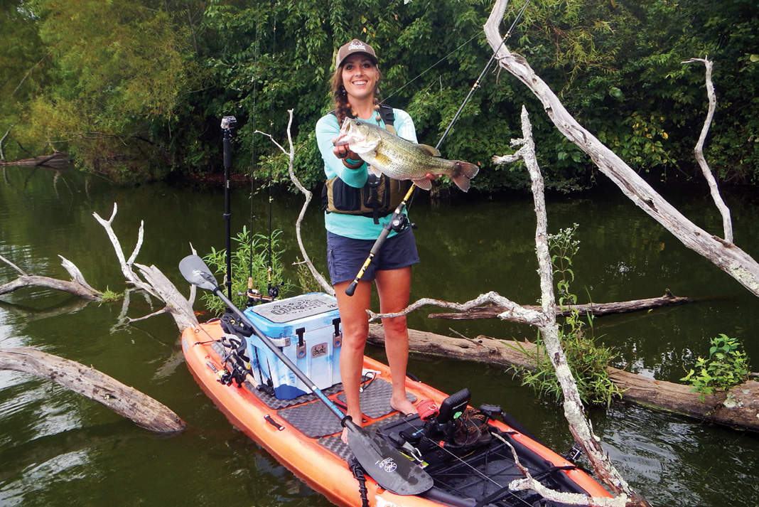 woman holds up a largemouth bass caught while sight fishing