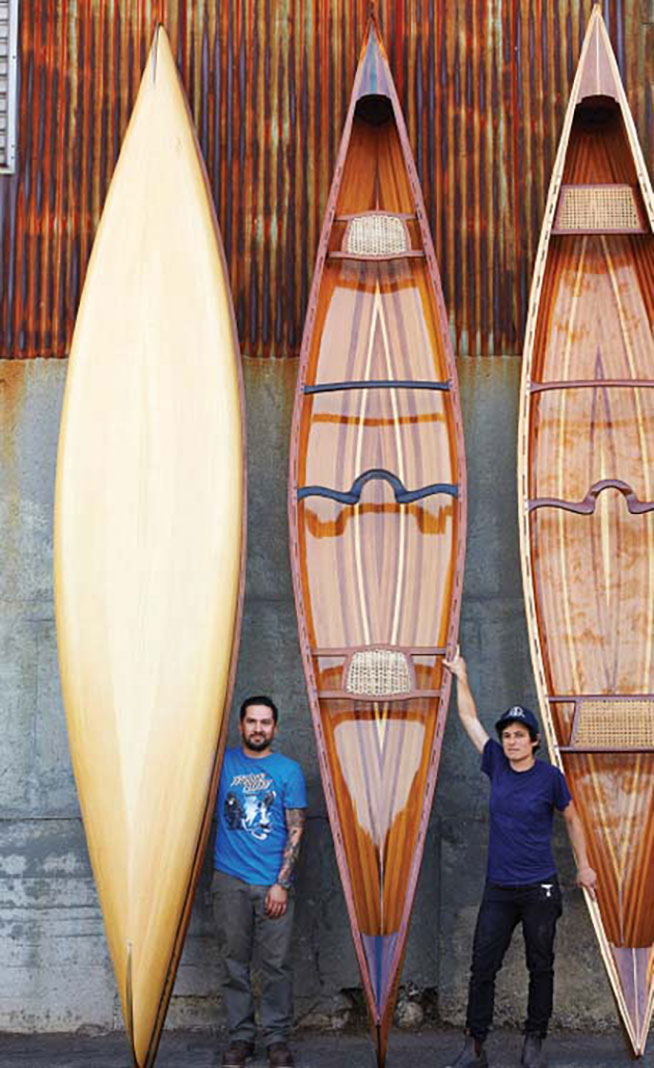 two people pose beside fine handcrafted wooden canoes from Offerman Workshop