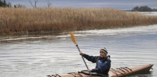 woman paddles a wooden Pygmy Murrelet kayak