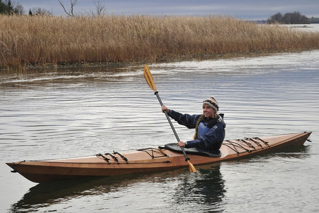 woman paddles a wooden Pygmy Murrelet kayak