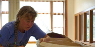 woman works on building a Pygmy Murrelet kayak in a workshop