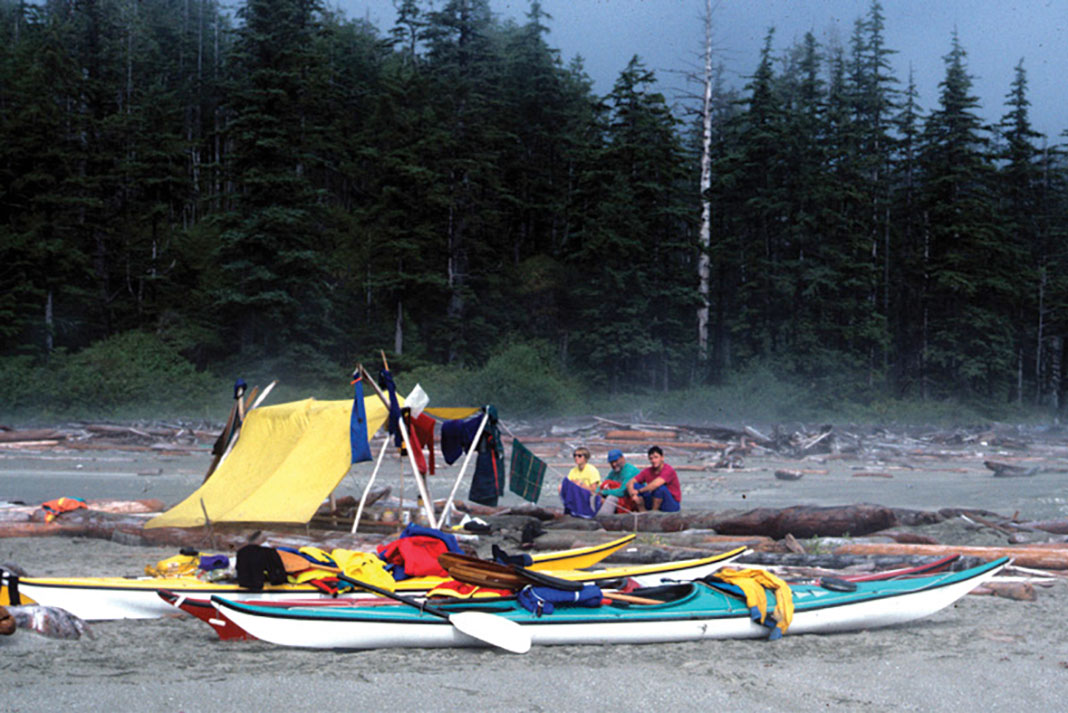 a group of people sit at a sea kayaking campsite on the west coast of Vancouver Island
