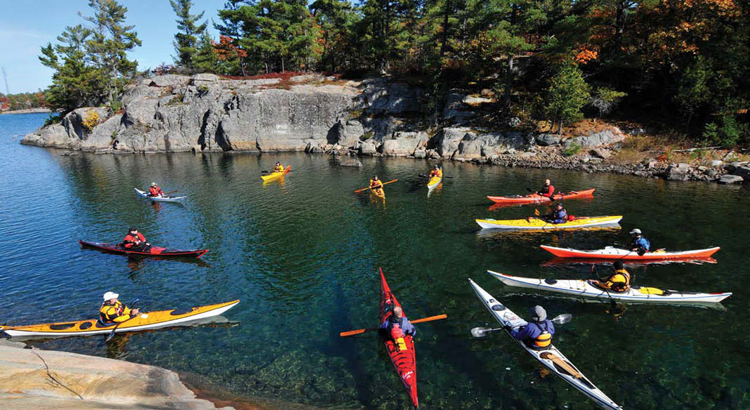a group of sea kayakers gather in a circle in a Georgian Bay cove
