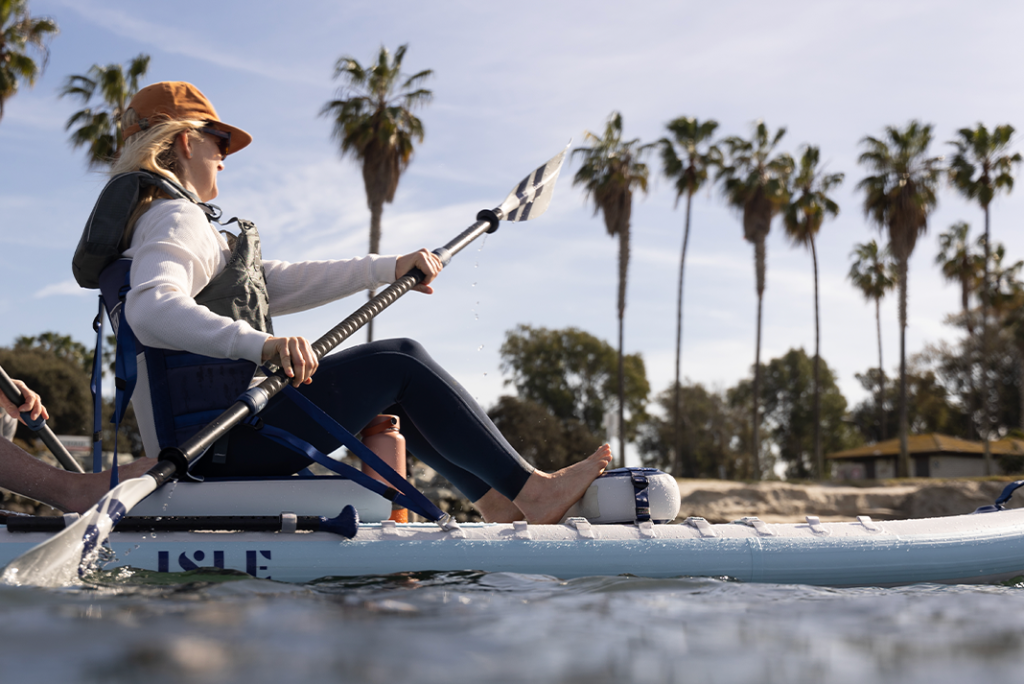 Woman paddling sitting down on a SUP.