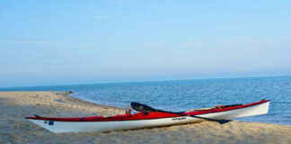 red touring kayak sits on beach after Lake Michigan crossing