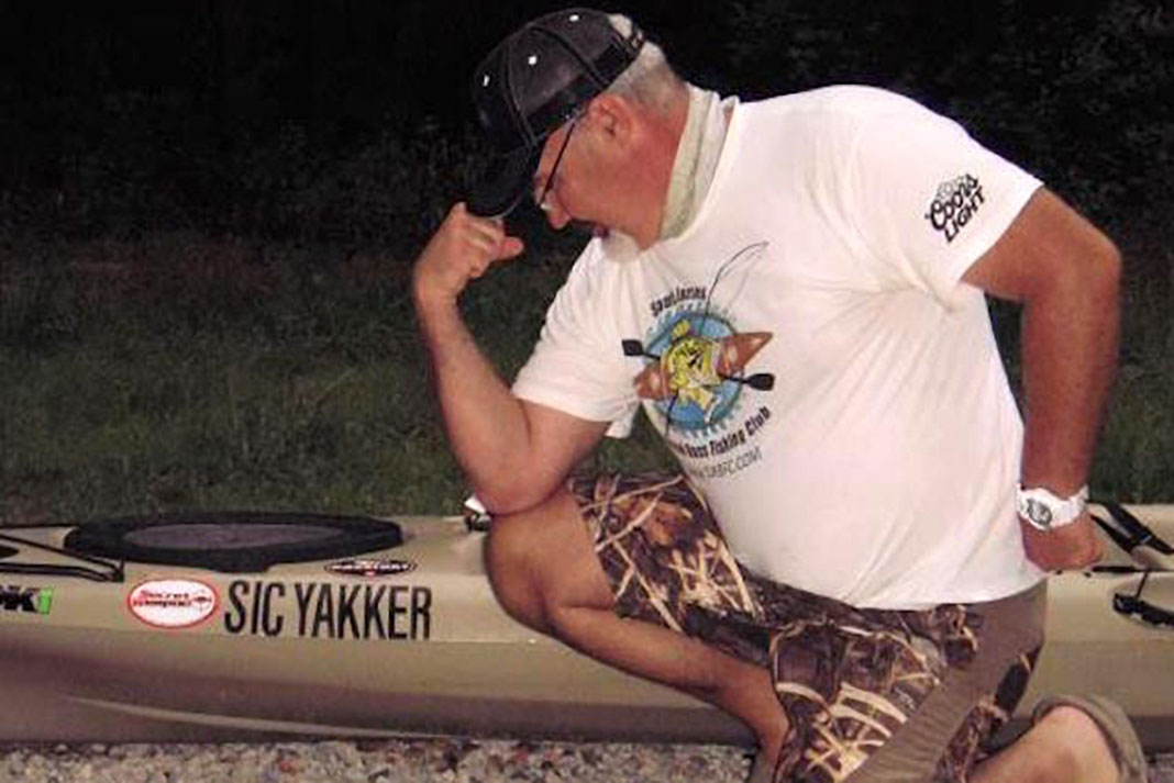 a know-it-all angler flexes beside his kayak