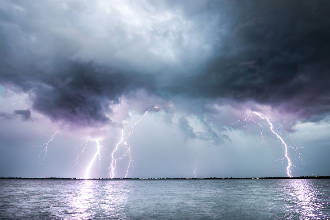 lightning strikes along the edge of a water body