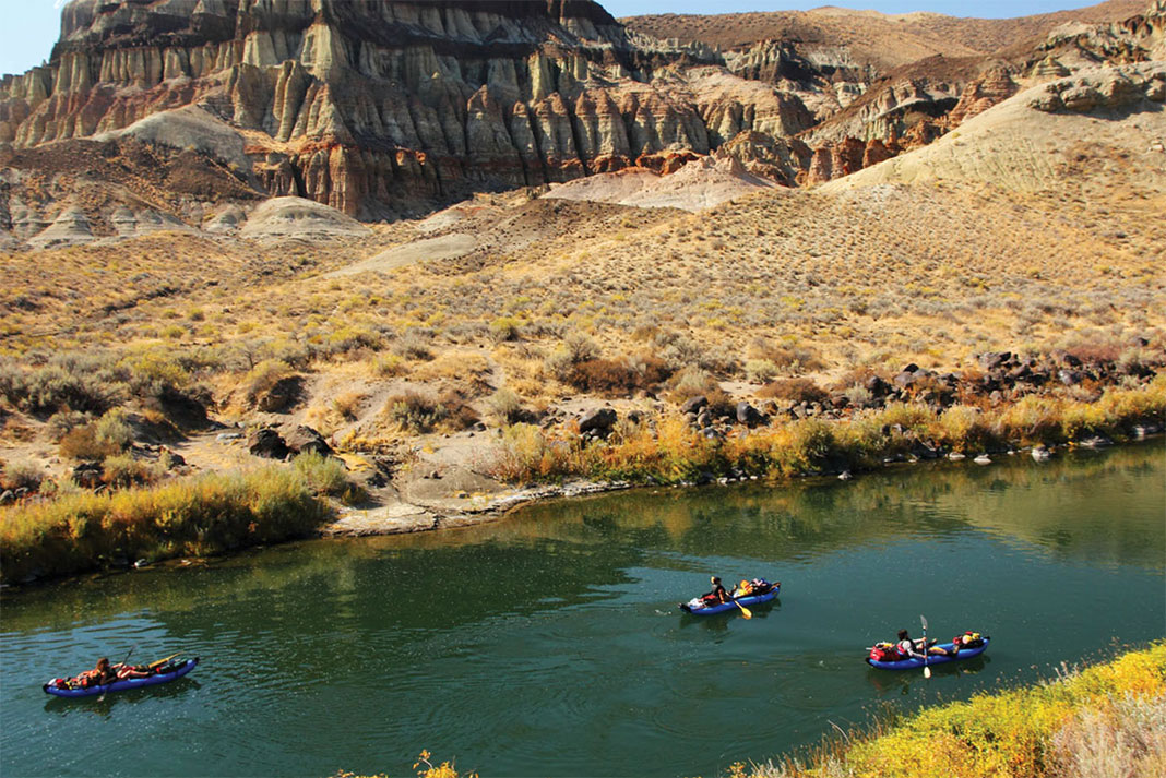 paddlers on the Owyhee River move through a desert landscape