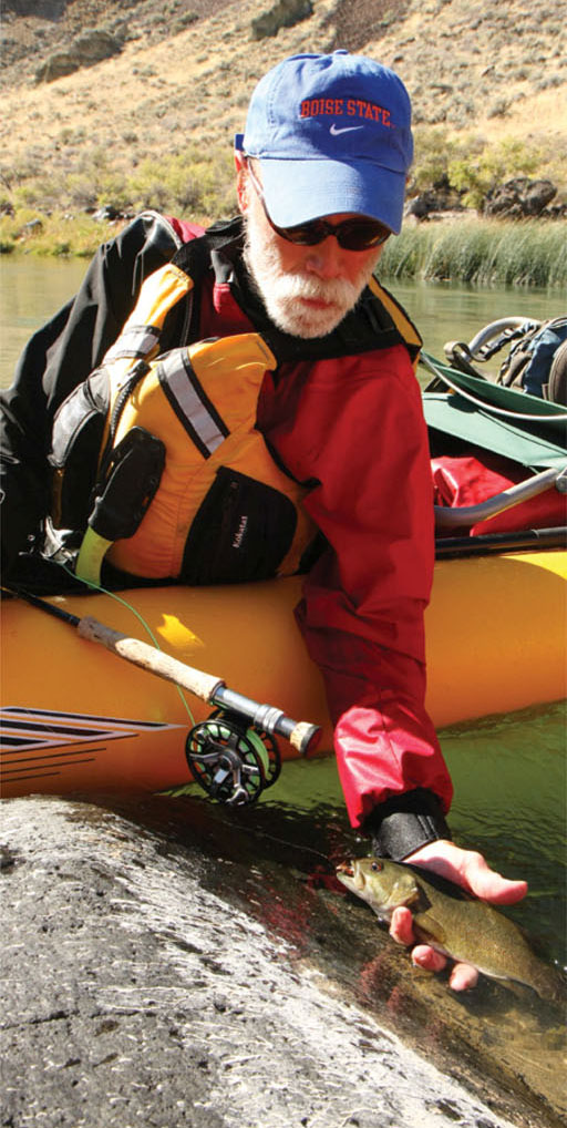 man in yellow kayak holds up a smallmouth bass