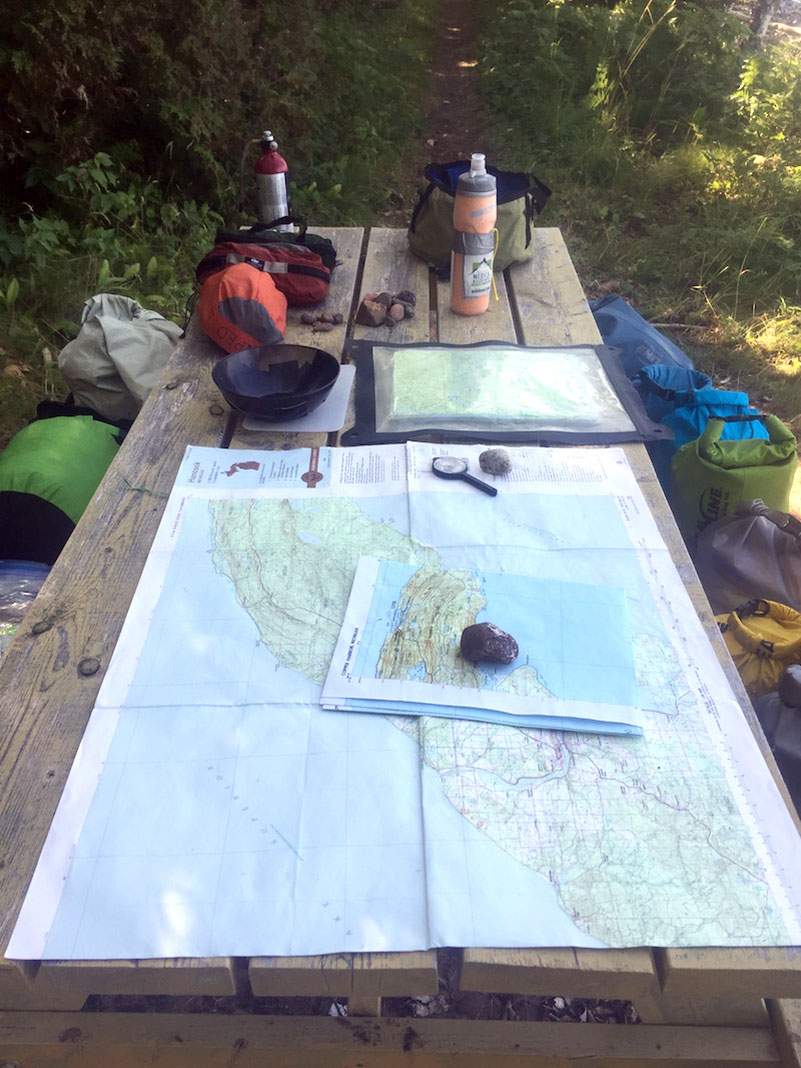 A map and other navigation tools spread out on a picnic table.