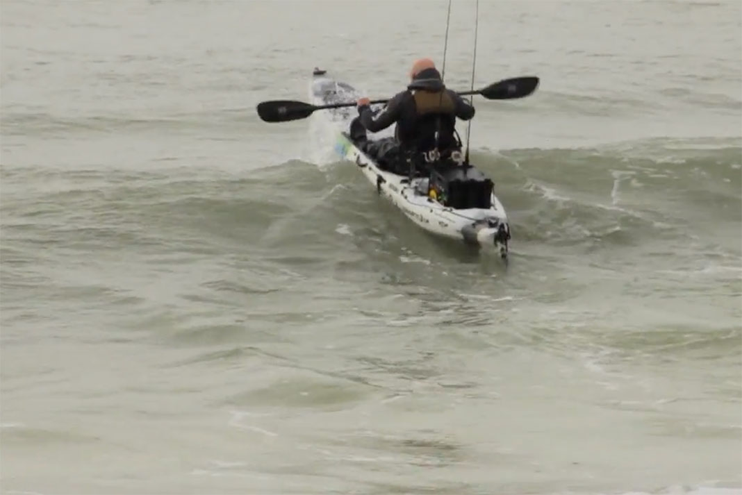 man in kayak demonstrates a surf launch