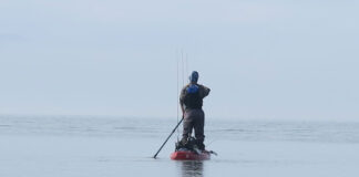 kayak angler stands and paddles quietly while fishing