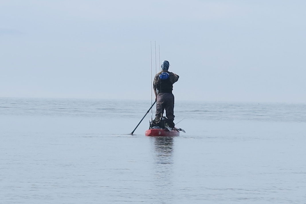 kayak angler stands and paddles quietly while fishing